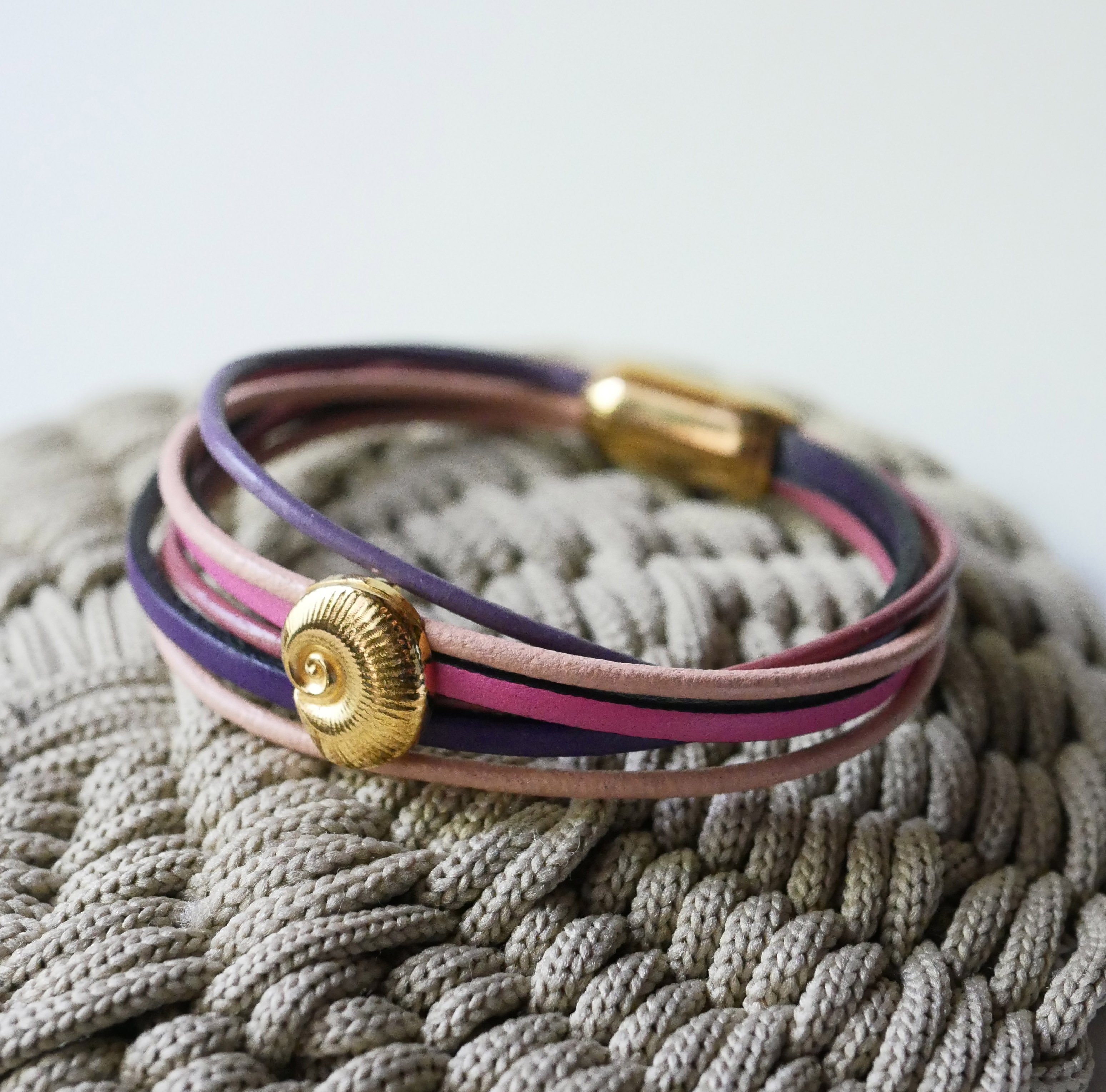 Bracelet multi-liens cuirs tons p&ecirc;ches et mauves d&eacute;cor coquillage dor&eacute;